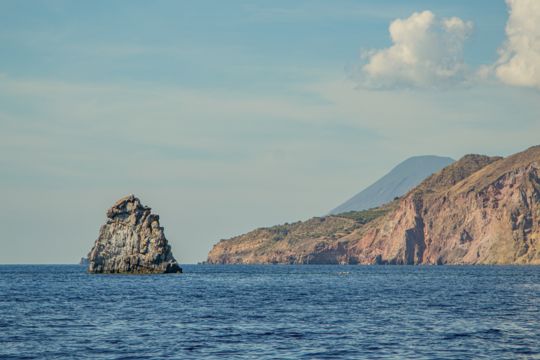 A rock formation with the volcanic coastline behind it